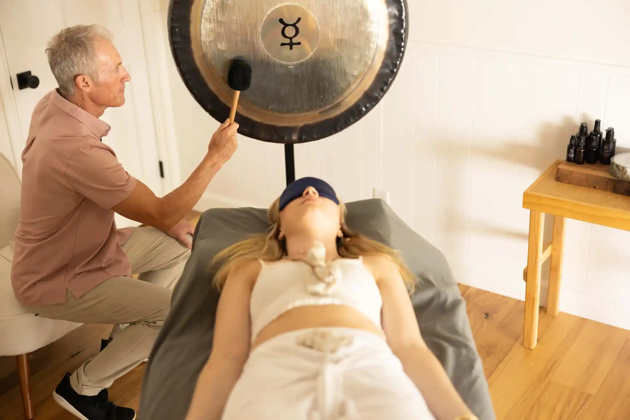 Practitioner playing a planet gong during private sound work at Camp Vortex Retreats