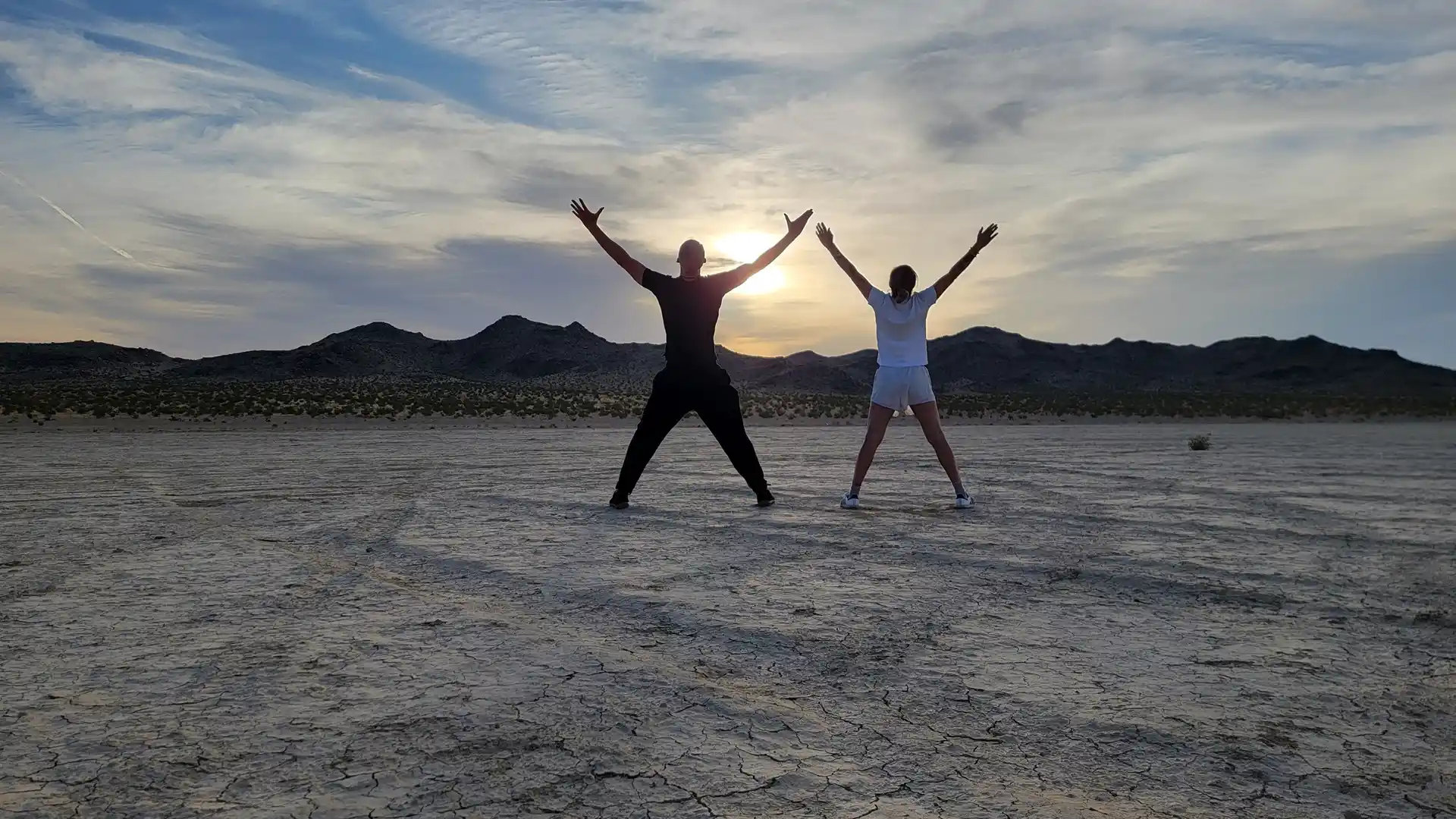 Two people celebrating with raised arms during an outdoor wellness retreat in the Joshua Tree desert.